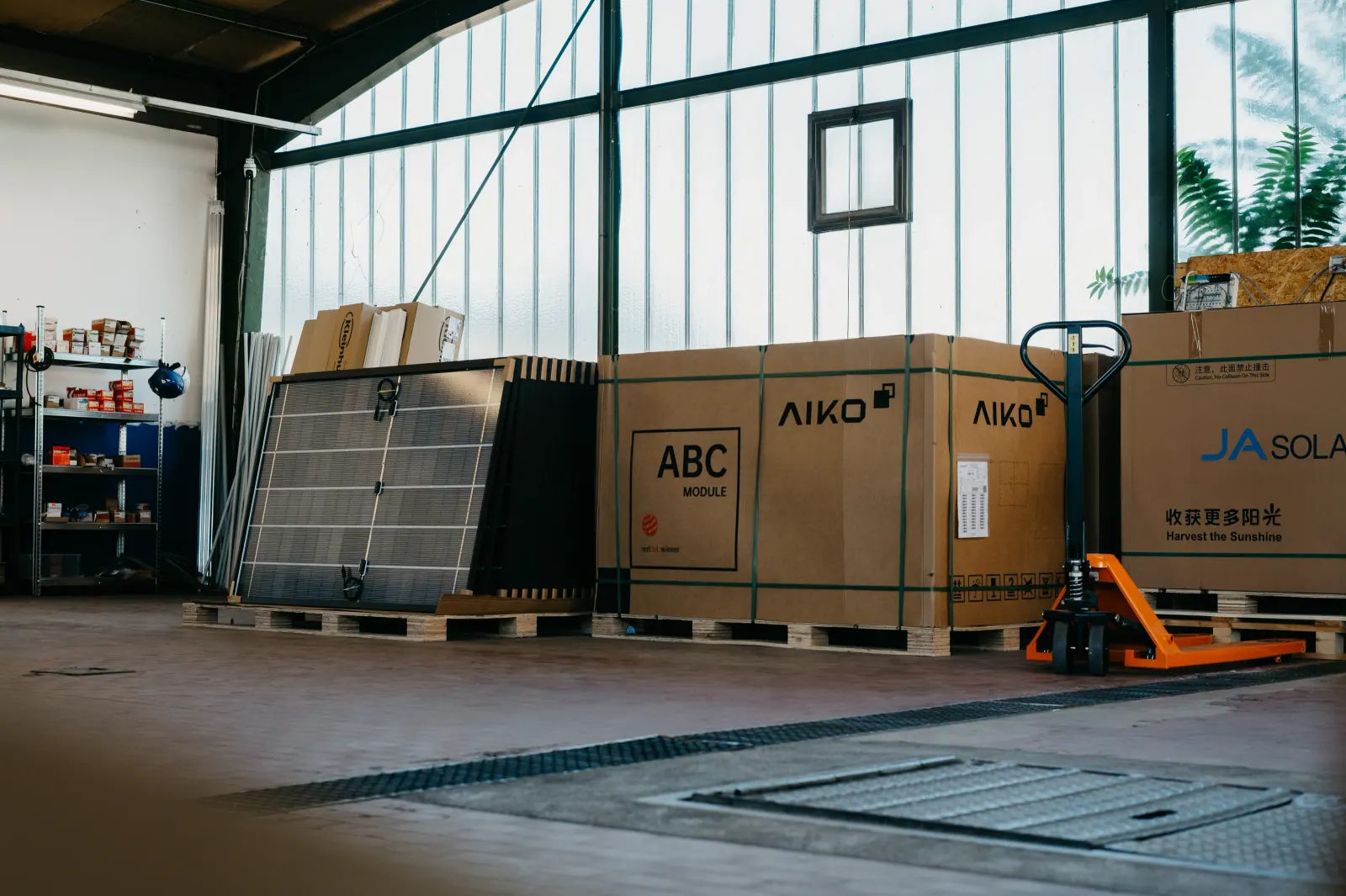 Lagerhalle mit palettierten Solarmodulen und einem Hubwagen
